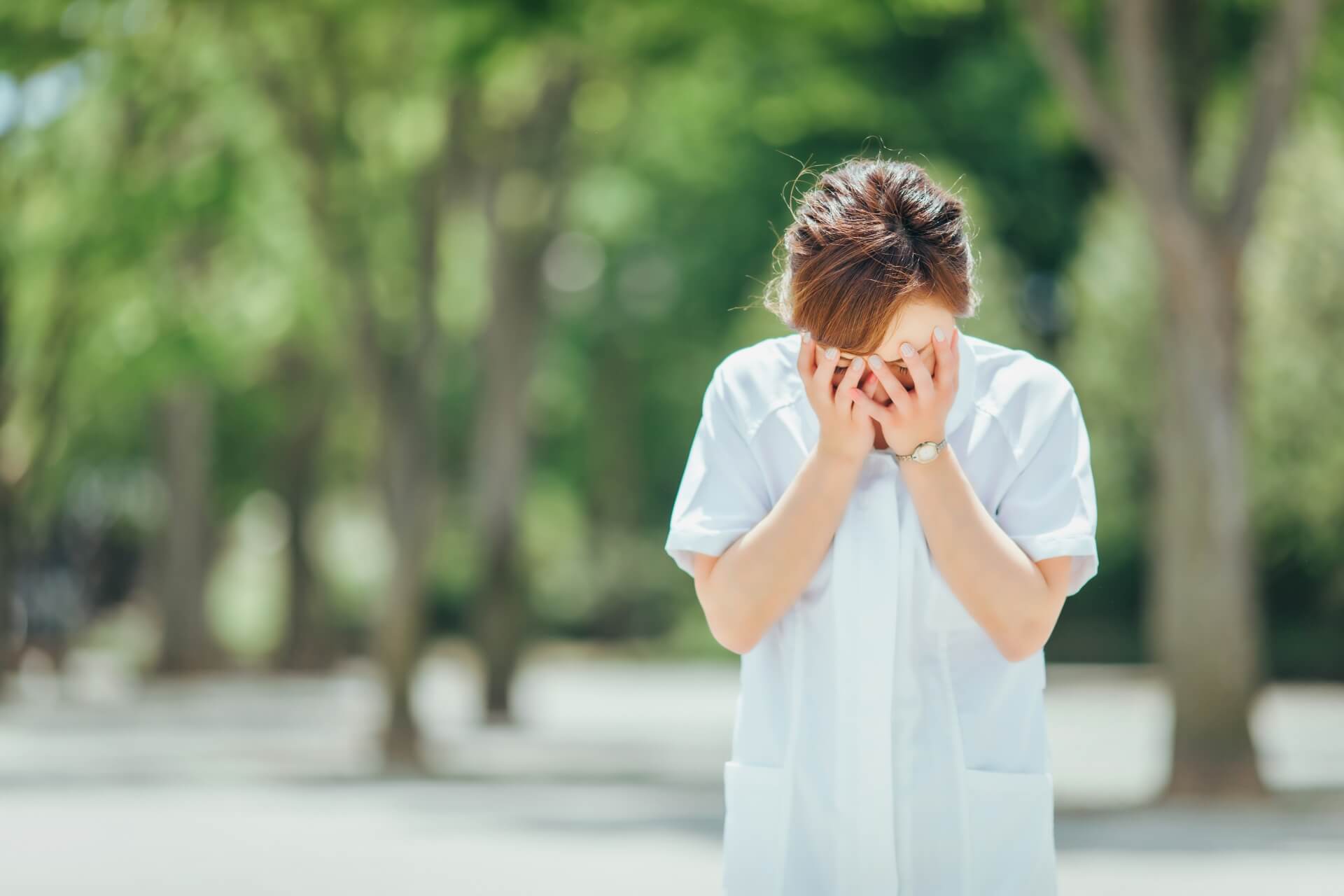 顔に両手をあて、うつむいている女性