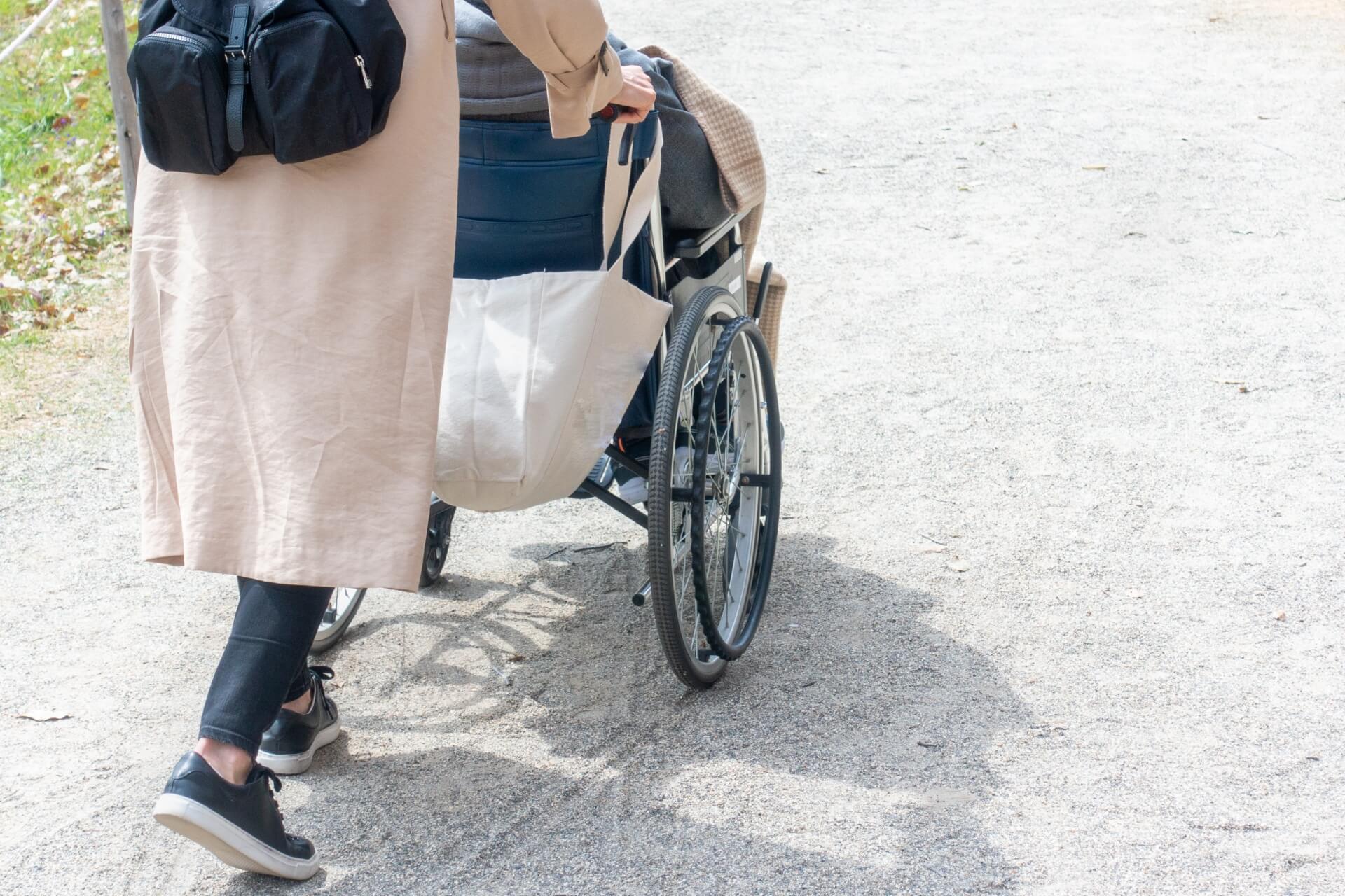 車いすを押す女性と車いすに乗った高齢者の後ろ姿